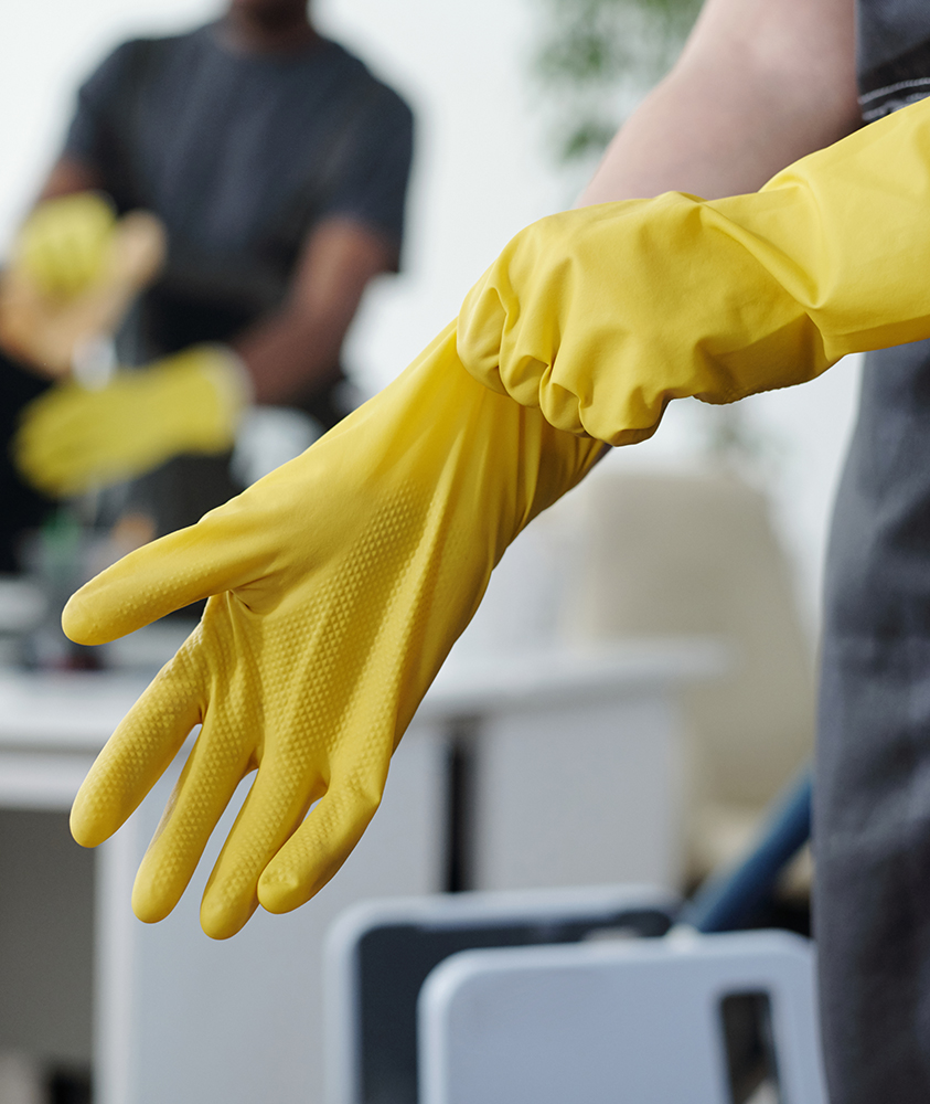 Cleaner pulling on yellow rubber gloves before a job
